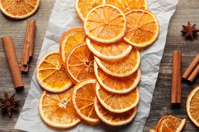 Photo of Many dry orange slices and spices on wooden table, flat lay