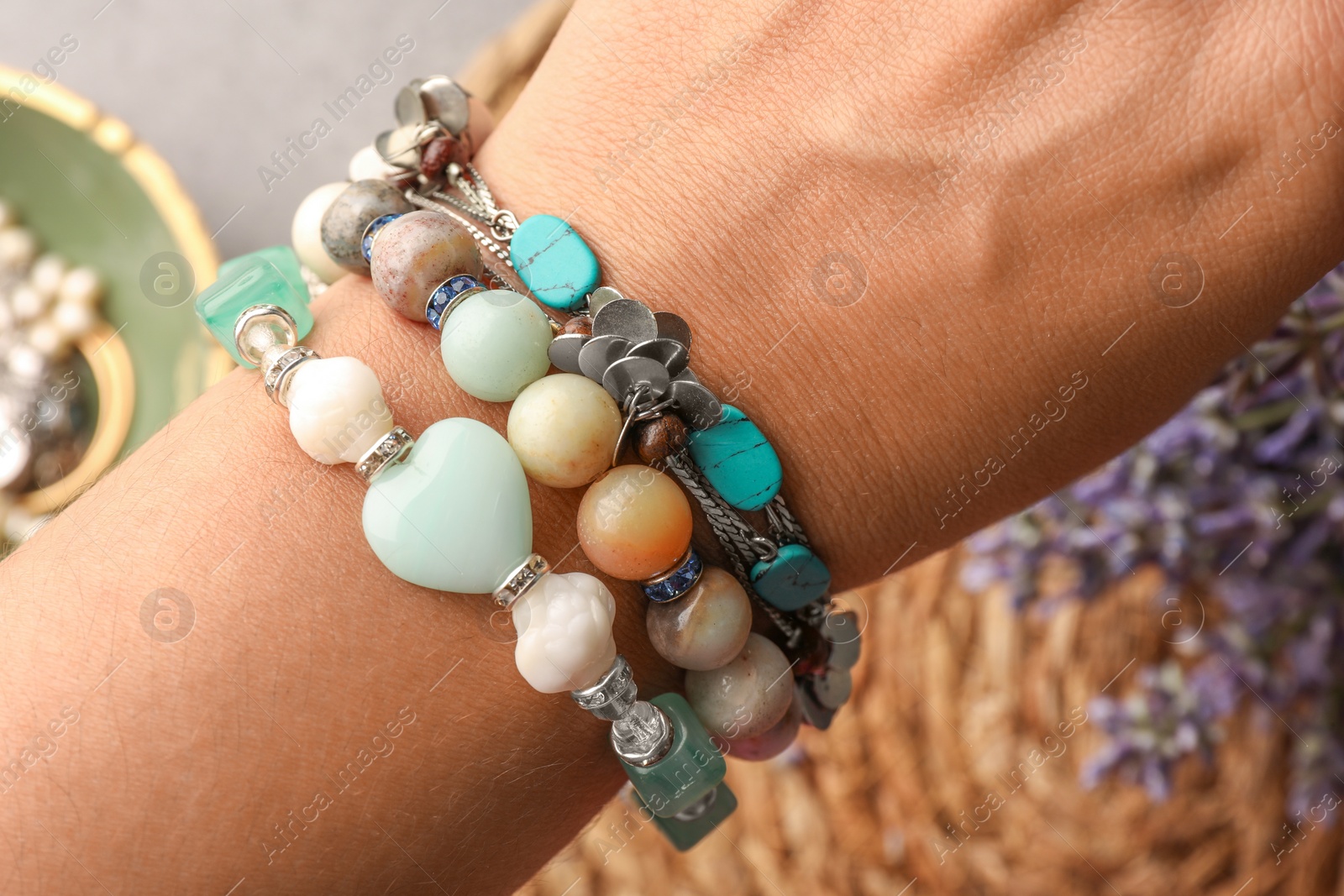 Photo of Woman wearing beautiful bracelets with gemstones on blurred background, closeup