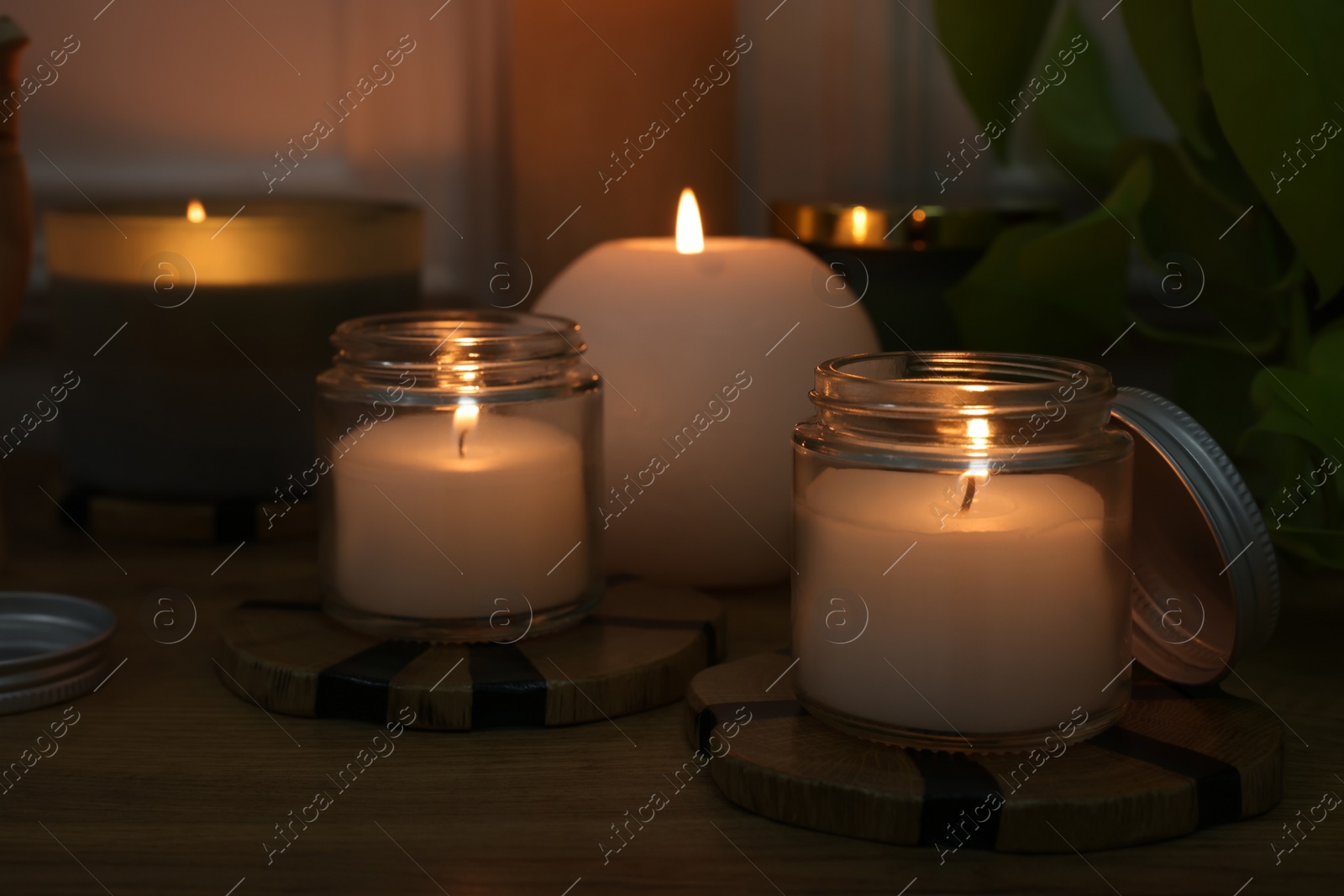 Photo of Burning candles on wooden table indoors, closeup