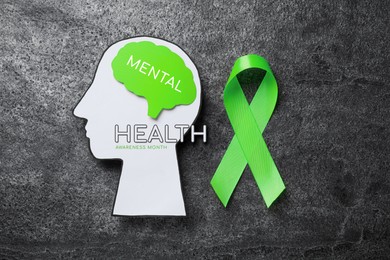 World Mental Health Day. Human head cutout, brain and green ribbon on grey table, flat lay