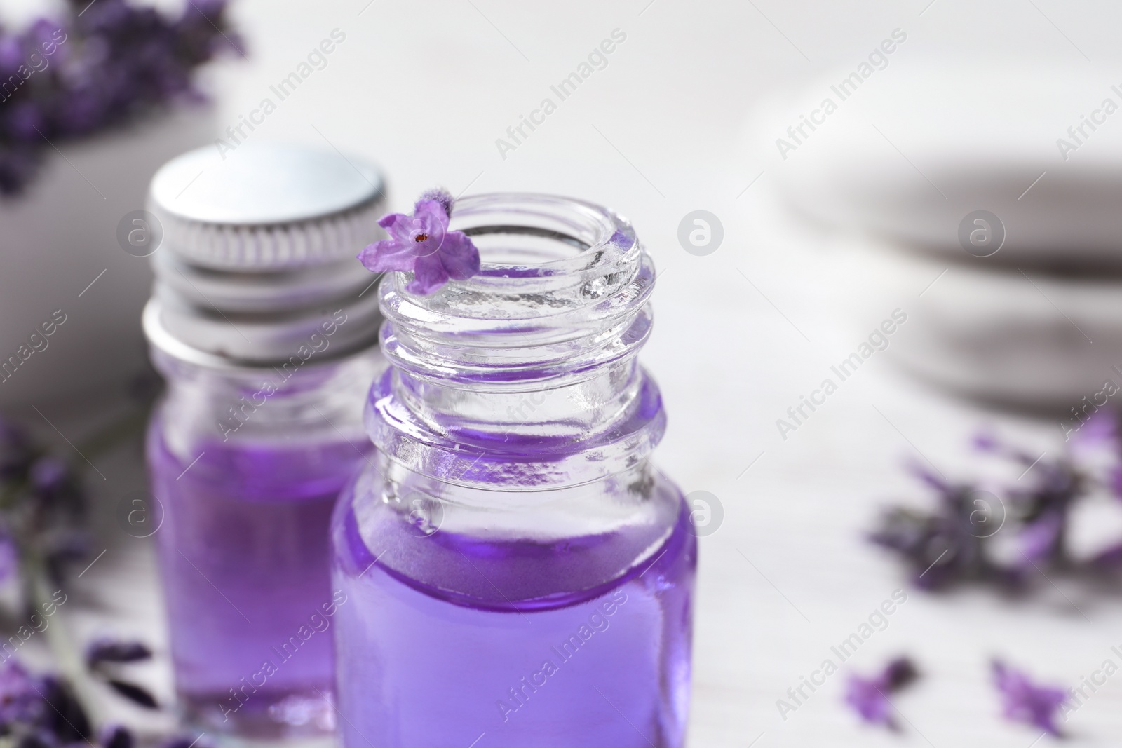 Photo of Glass bottles of natural cosmetic oil and lavender flowers on table, closeup