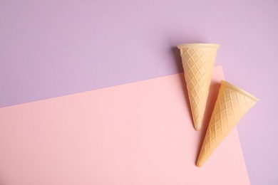 Photo of Empty wafer ice cream cones on color background, flat lay. Space for text