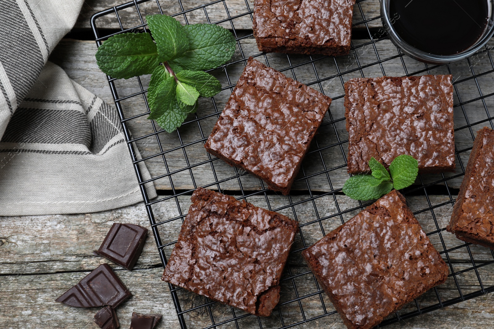Photo of Cooling rack with delicious chocolate brownies and fresh mint on wooden table, flat lay