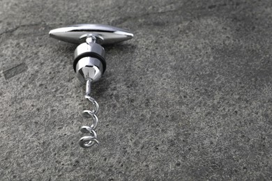 Photo of One metal corkscrew on grey textured table. Space for text
