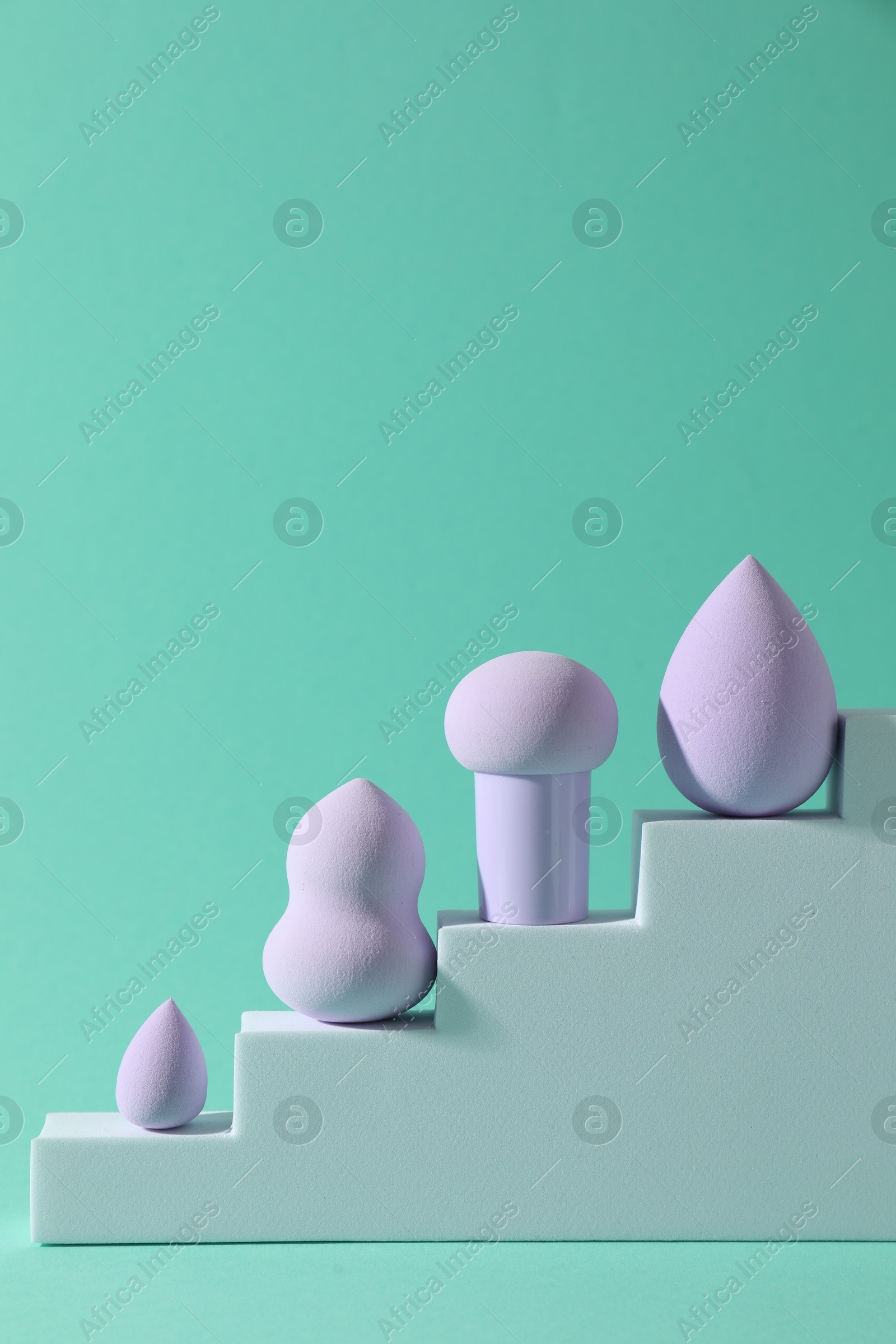 Photo of Stylish presentation of makeup sponges on turquoise background