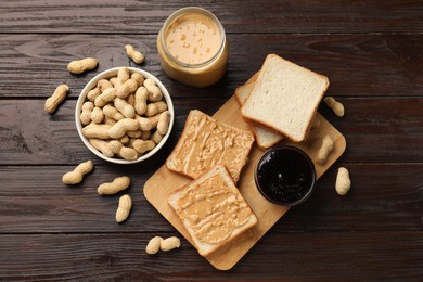 Photo of Delicious toasts with peanut butter, nuts and jam on dark wooden table, flat lay