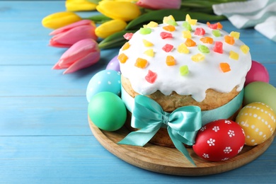 Photo of Easter cake, color eggs and tulips on blue wooden table, space for text