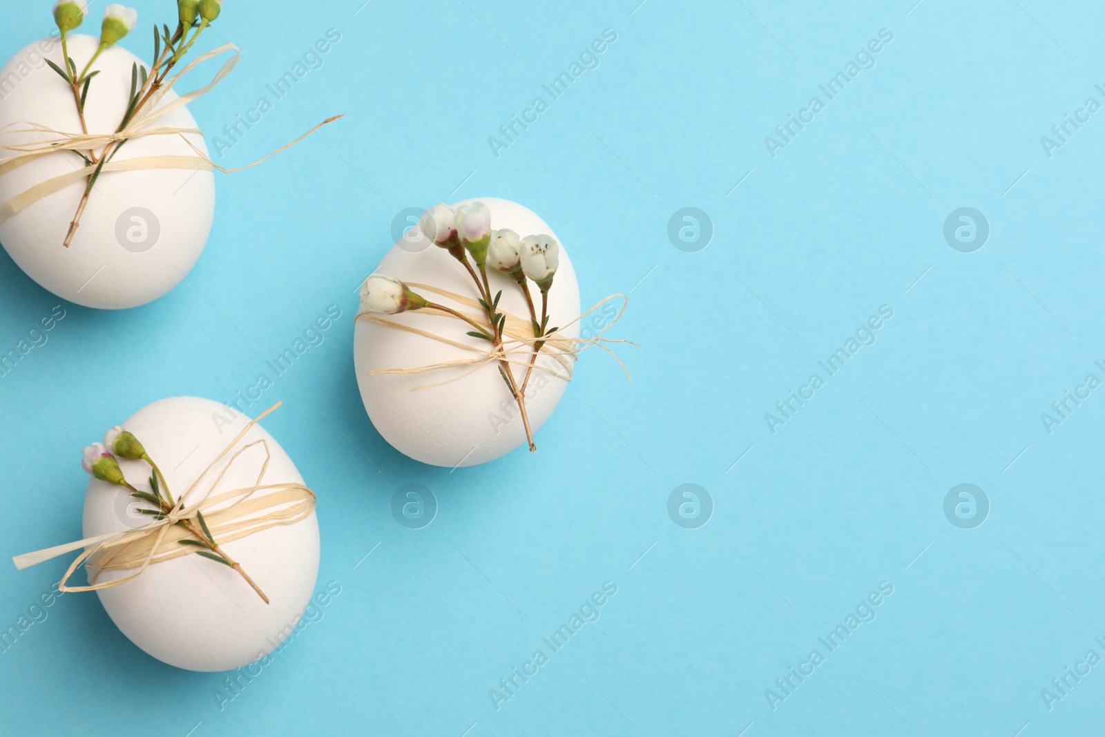 Photo of Festively decorated chicken eggs on light blue background, flat lay with space for text. Happy Easter