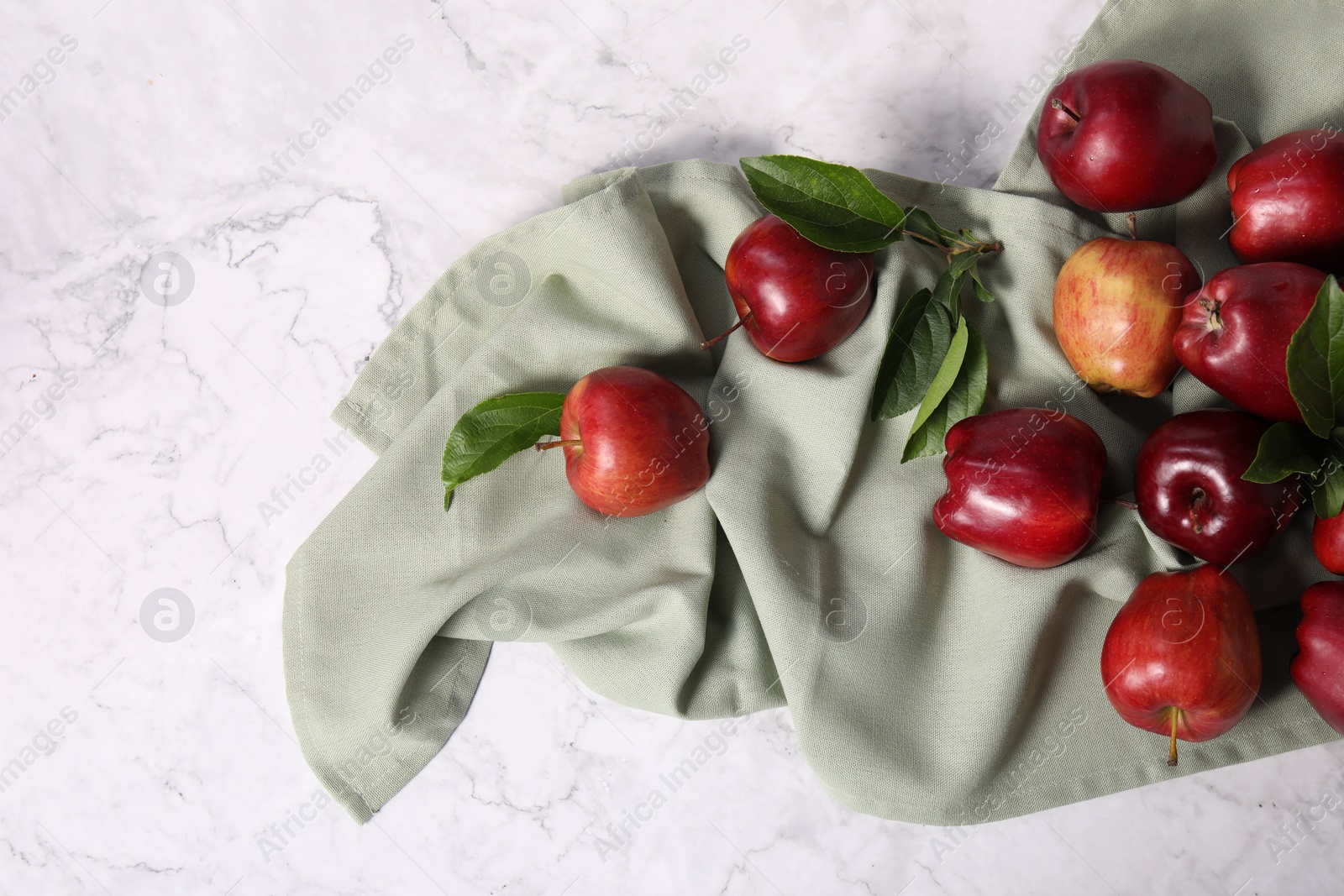 Photo of Fresh red apples with leaves on white marble table. Space for text