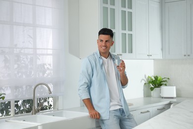 Man with glass of tap water in kitchen