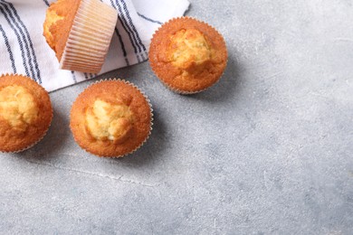 Photo of Delicious sweet muffins on light grey textured table, flat lay. Space for text