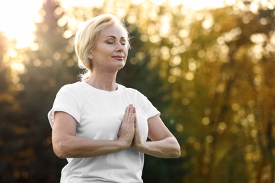 Image of Mature woman practicing yoga outdoors in morning