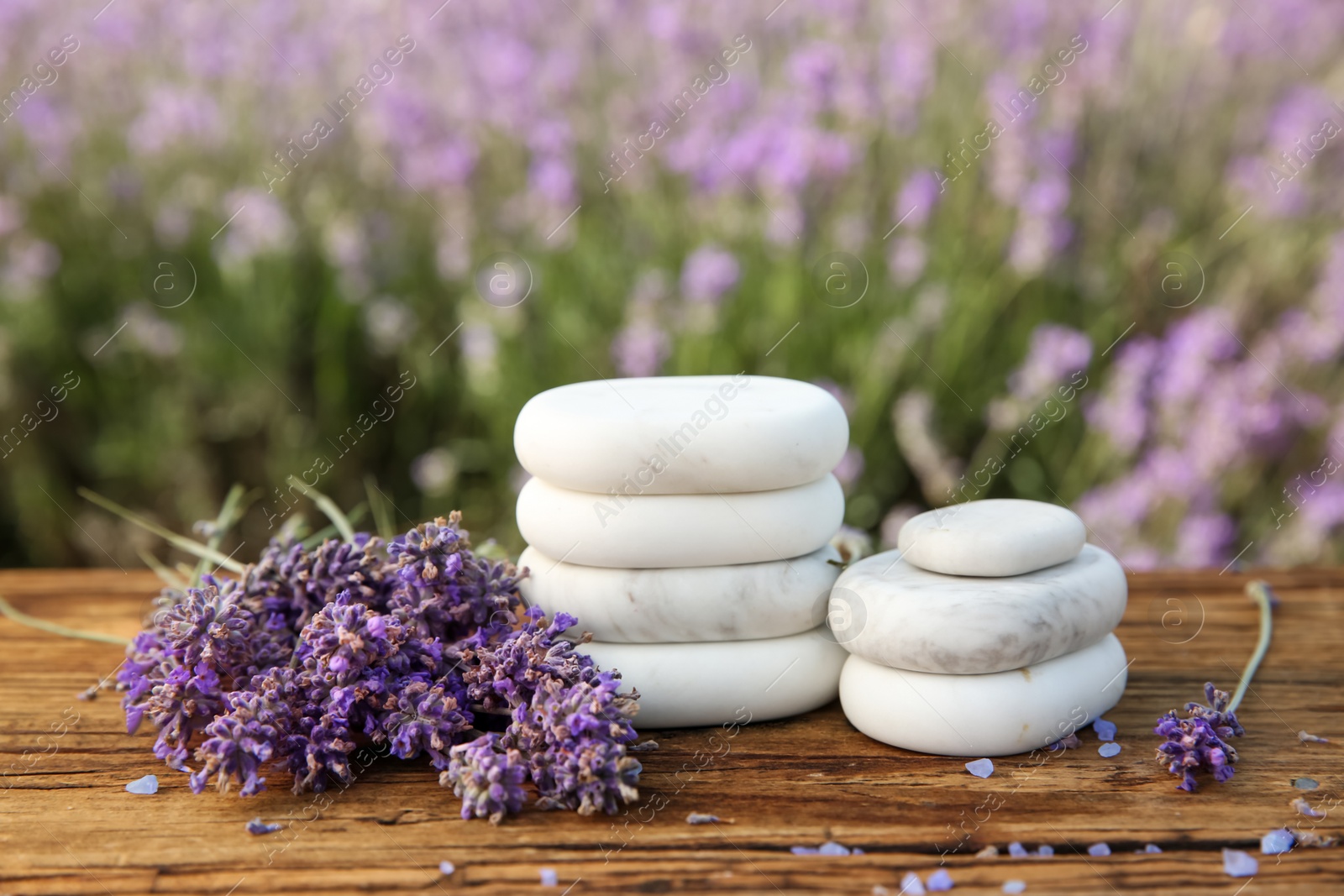 Photo of Spa stones, fresh lavender flowers and bath salt on wooden table outdoors, closeup