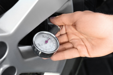 Photo of Mechanic checking tire air pressure at car service, closeup