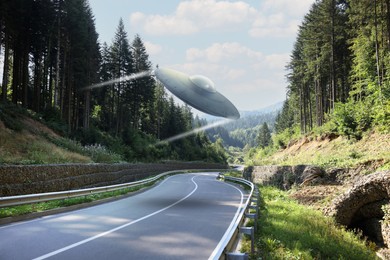 Image of Alien spaceship flying over road in mountains. UFO