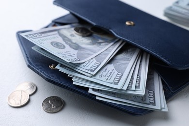 Photo of Dollar banknotes in wallet and coins on white table, closeup. Money exchange