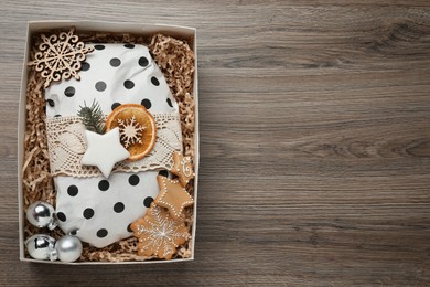 Photo of Wrapped Christmas Stollen and decoration in box on wooden table, top view. Space for text
