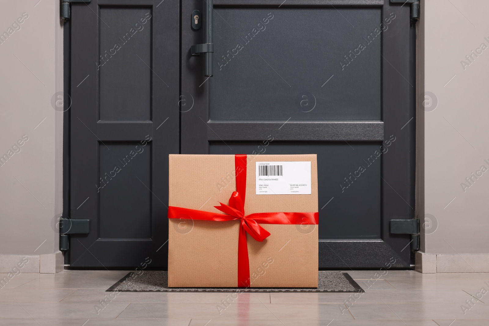 Photo of Christmas gift box on floor near door. Sending present by mail