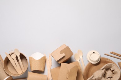 Photo of Eco friendly food packaging. Paper containers and tableware on light grey background, flat lay. Space for text