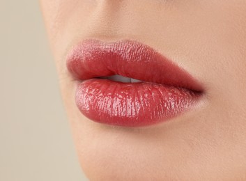Image of Woman with beautiful perfect lips after permanent makeup procedure on beige background, closeup