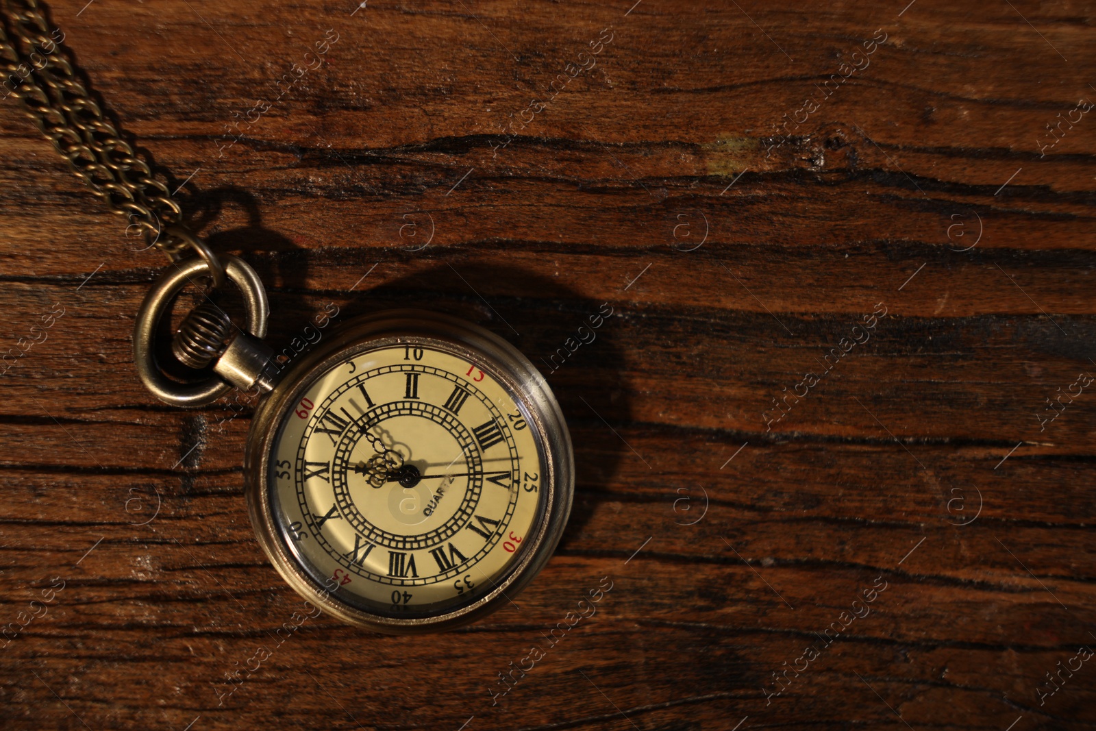 Photo of Pocket clock with chain on wooden table, top view. Space for text