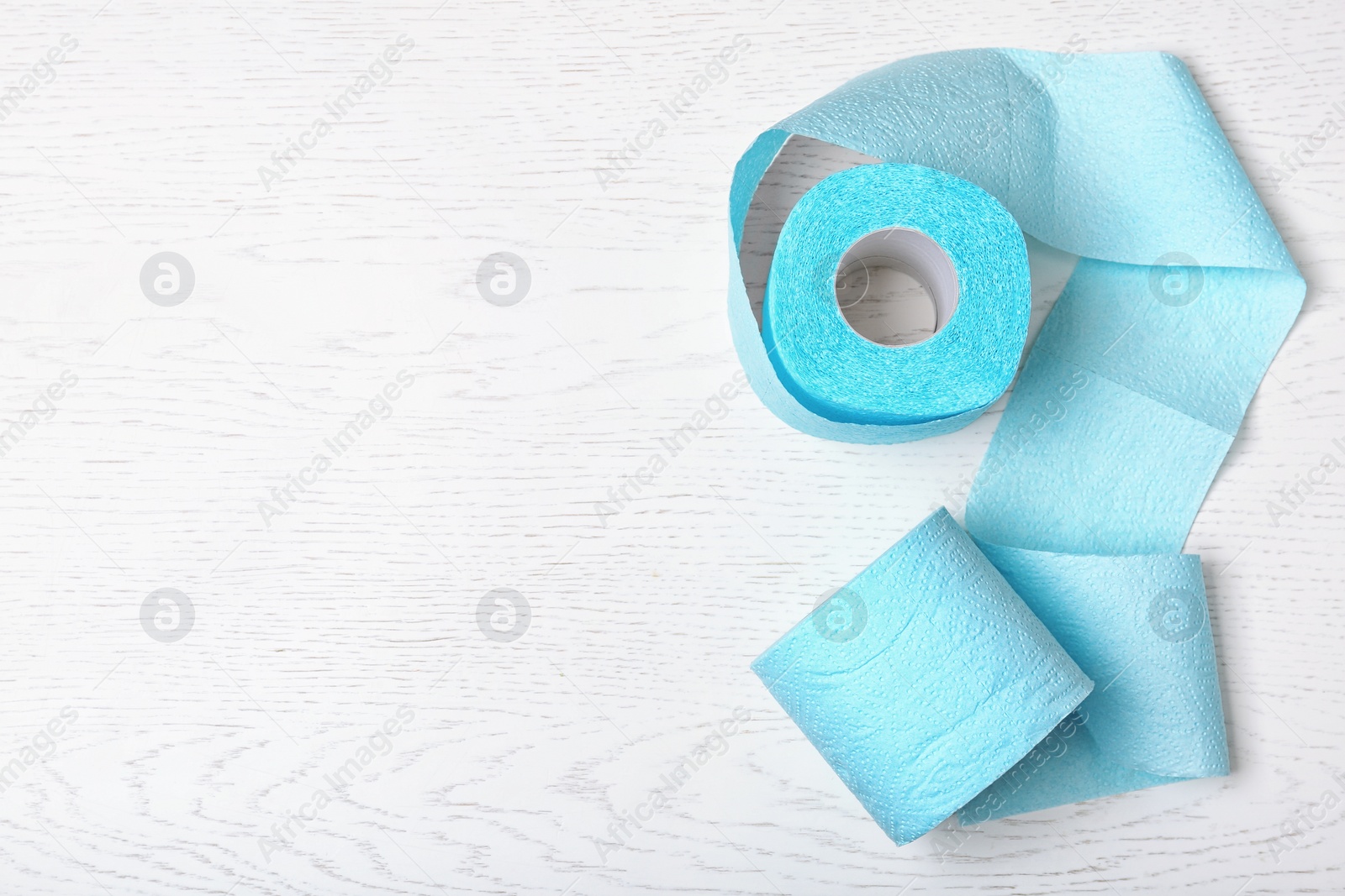 Photo of Toilet paper rolls on white wooden background, top view. Space for text