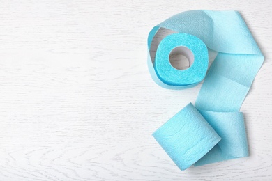 Toilet paper rolls on white wooden background, top view. Space for text