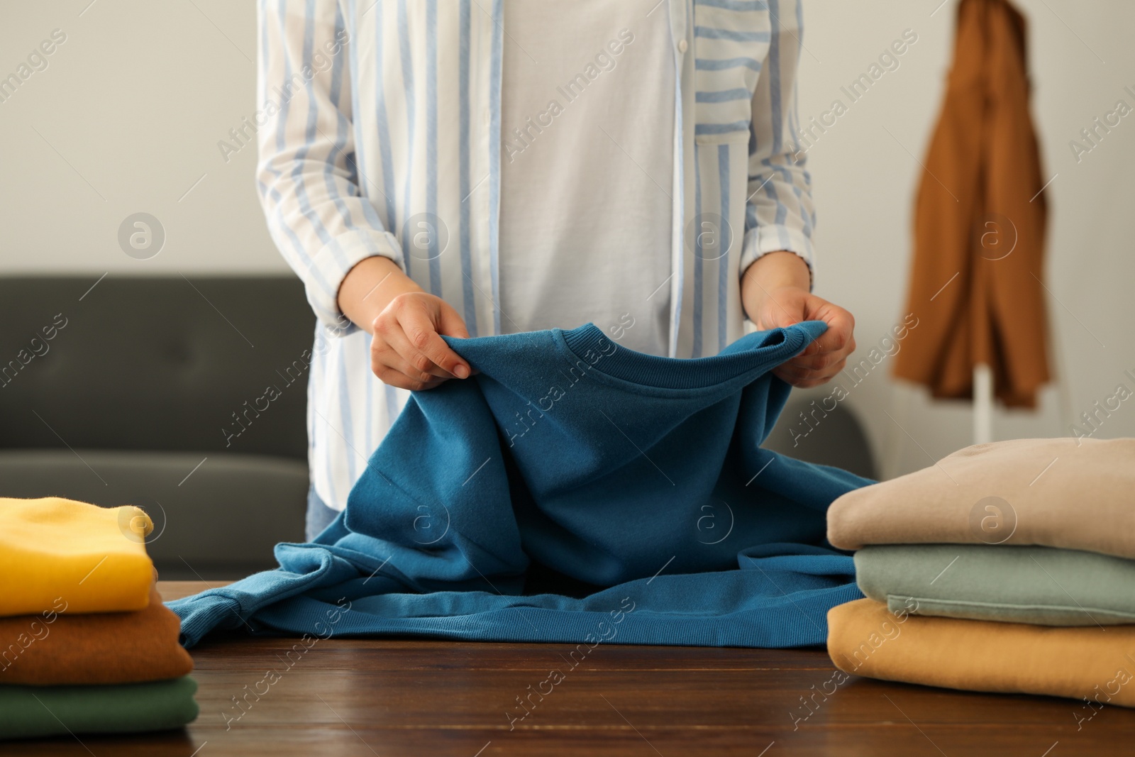 Photo of Woman folding clothes at wooden table indoors, closeup