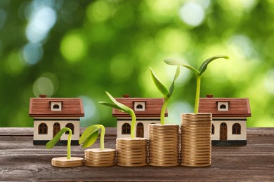 Real estate investing. House models and coins on wooden table