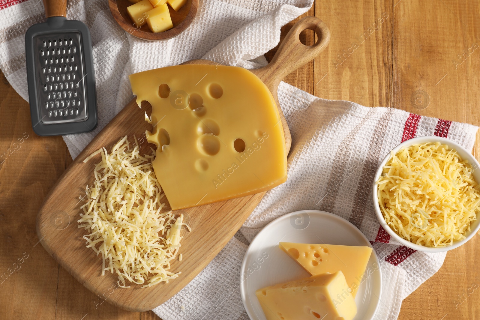 Photo of Grated, cut cheese and grater on wooden table, flat lay