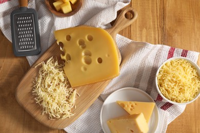 Photo of Grated, cut cheese and grater on wooden table, flat lay