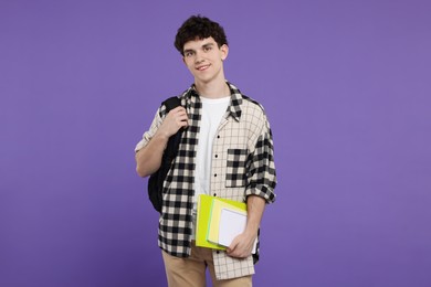 Portrait of student with backpack and notebooks on purple background
