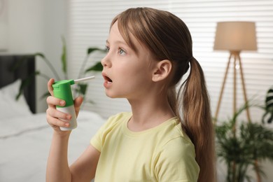 Photo of Little girl using throat spray at home