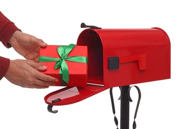 Man putting Christmas gift into mailbox on white background, closeup. Sending present by mail