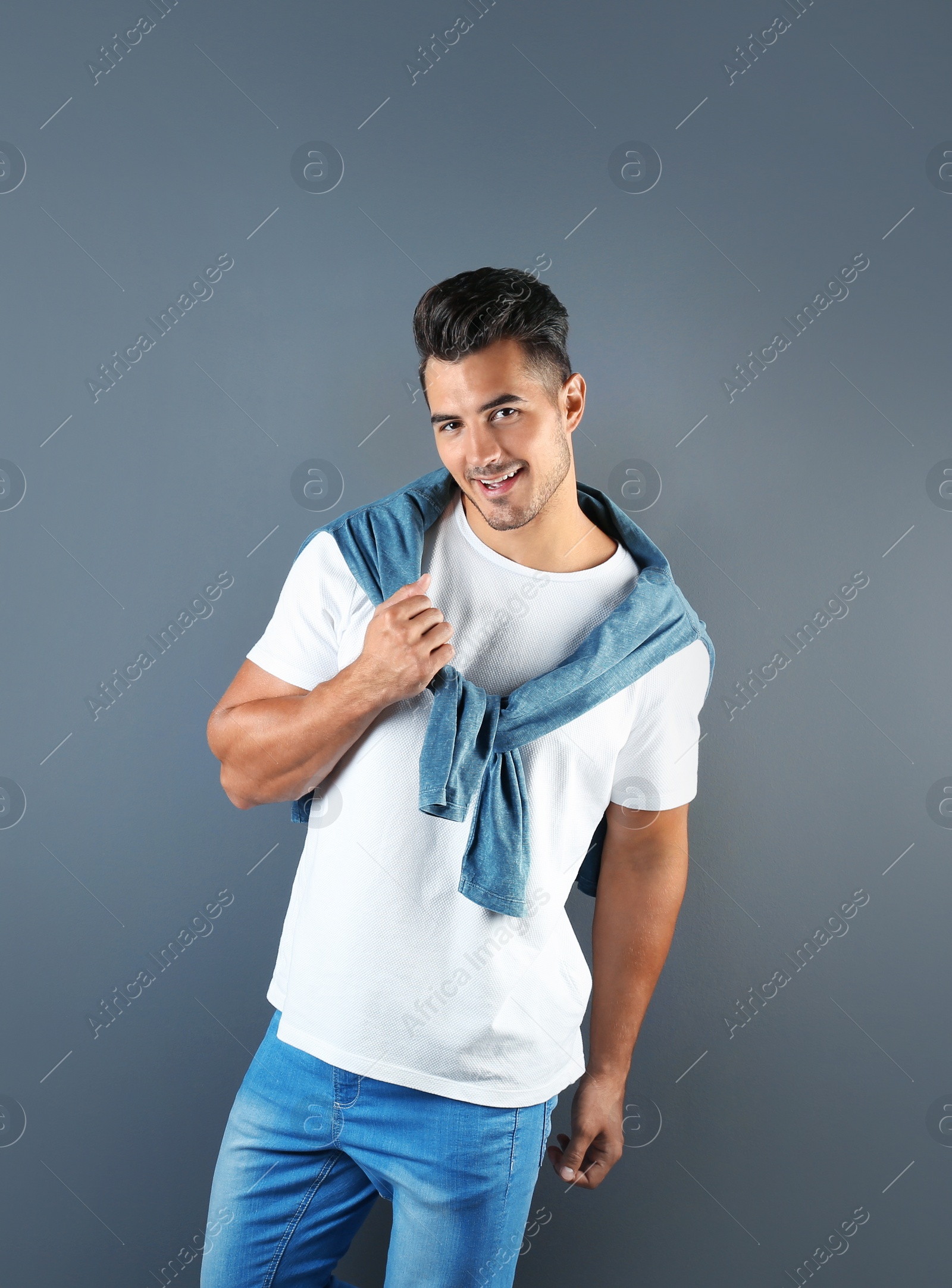 Photo of Young man in stylish jeans on grey background