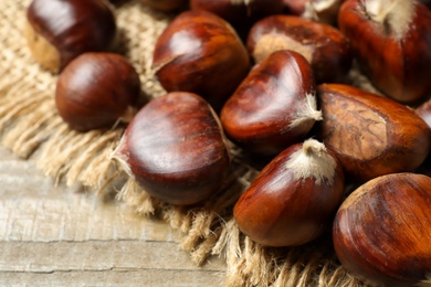 Fresh sweet edible chestnuts on wooden table, closeup