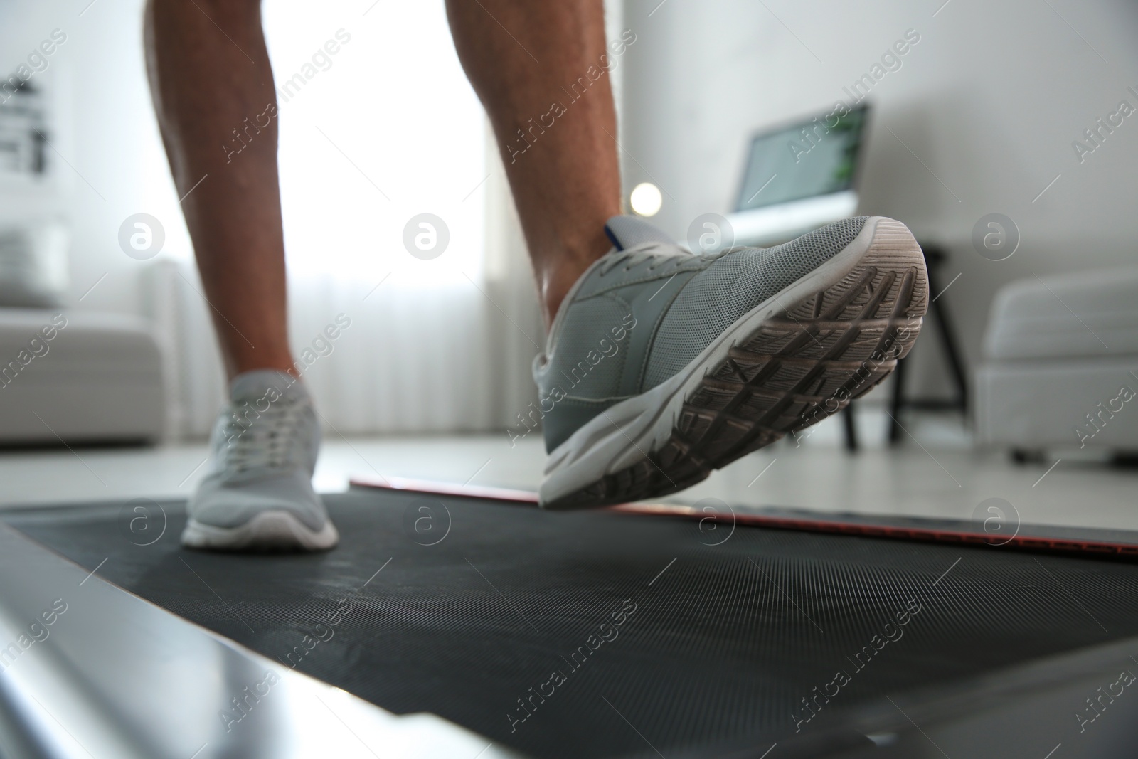 Photo of Sporty man training on walking treadmill at home, closeup