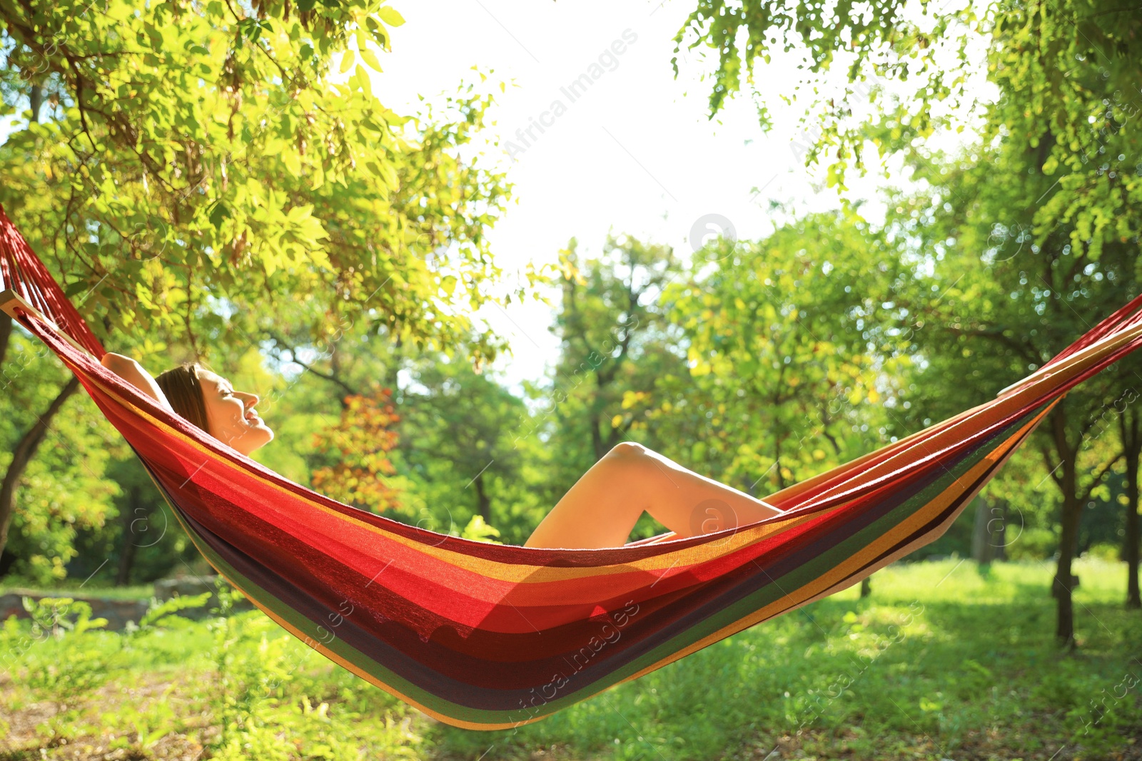 Photo of Young woman resting in comfortable hammock at green garden