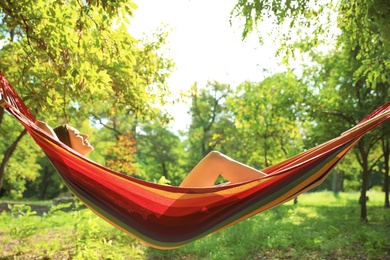 Young woman resting in comfortable hammock at green garden