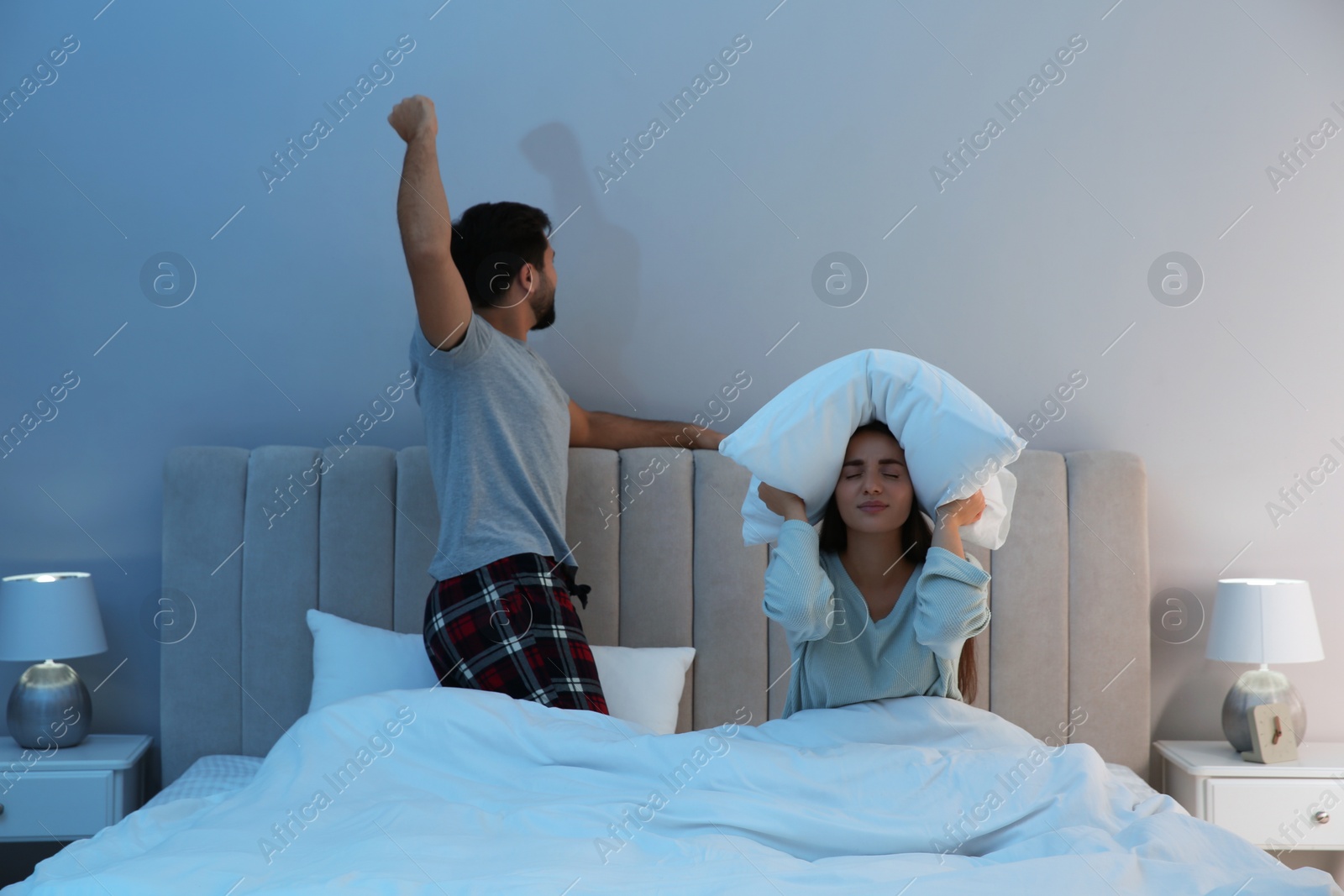 Photo of Young couple suffering from noisy neighbours in bed at home