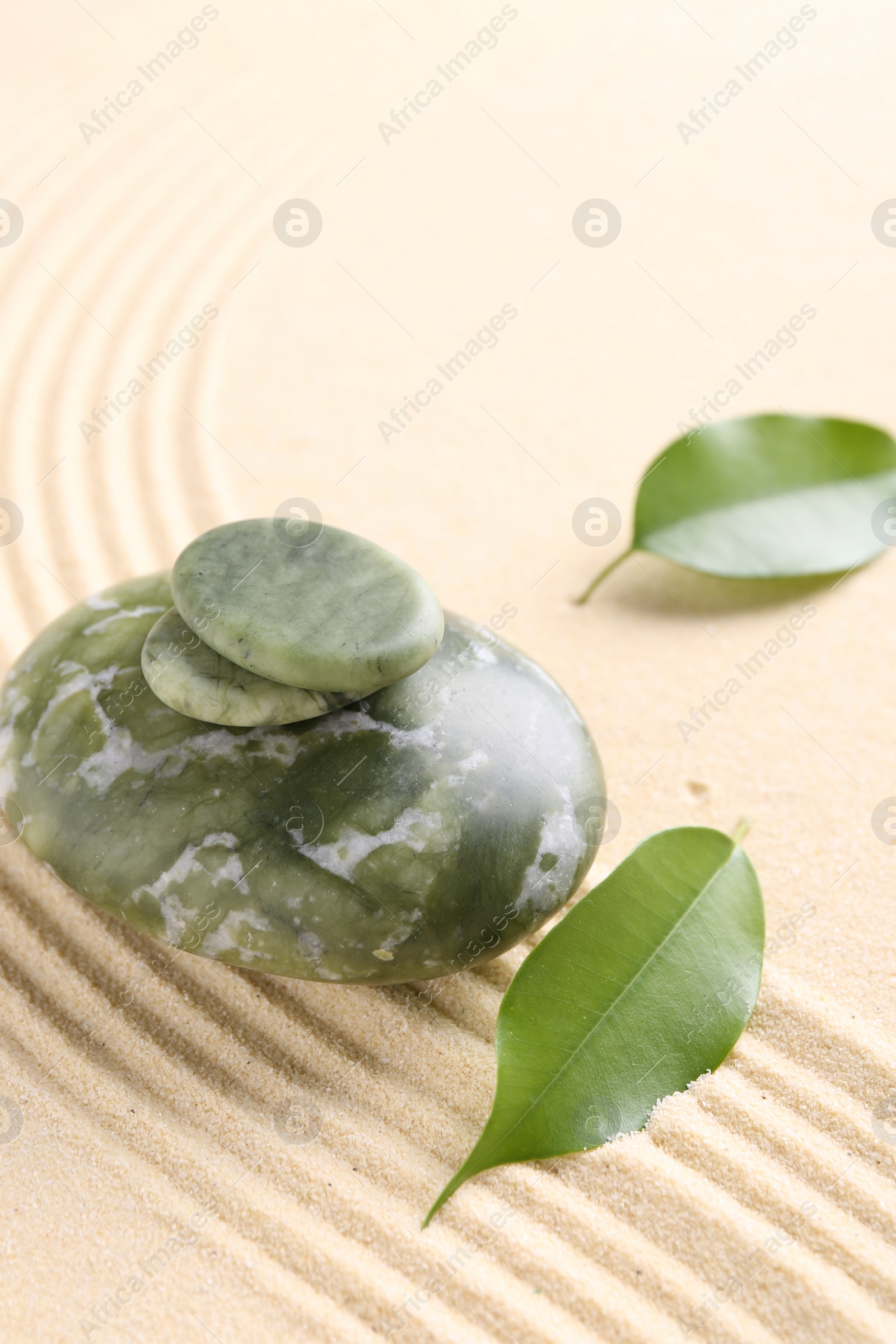 Photo of Zen garden stones and leaves on beige sand with pattern