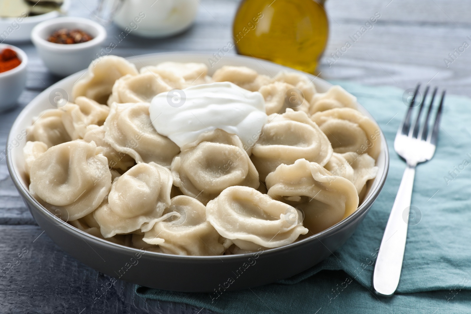 Photo of Tasty dumplings in bowl served on grey table, closeup