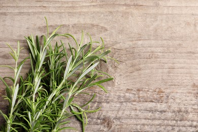 Photo of Fresh rosemary sprigs on wooden table, flat lay. Space for text