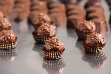 Many delicious chocolate candies on grey table. Production line