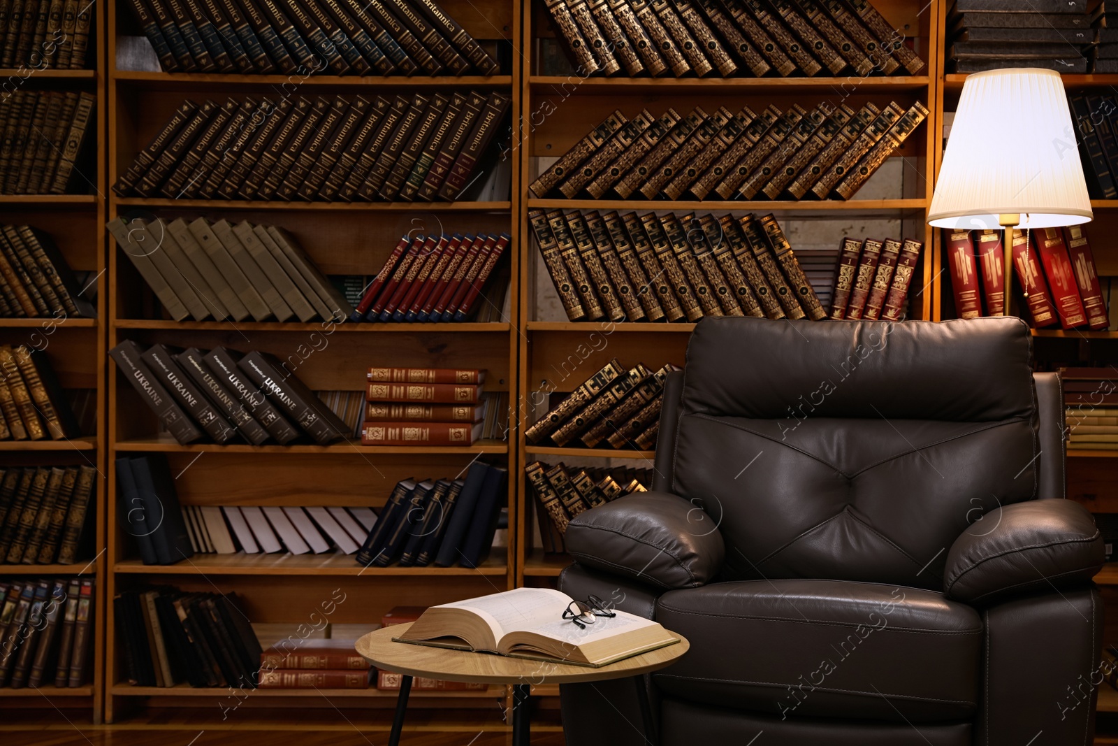 Photo of Cozy home library interior with leather armchair and collection of vintage books on shelves