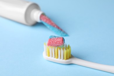 Photo of Toothbrush and tube with gummy candies on light blue background, closeup. Dangers of sugar
