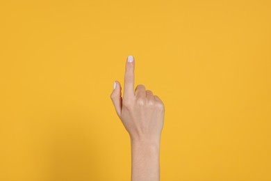 Photo of Woman pointing at something against yellow background, closeup on hand