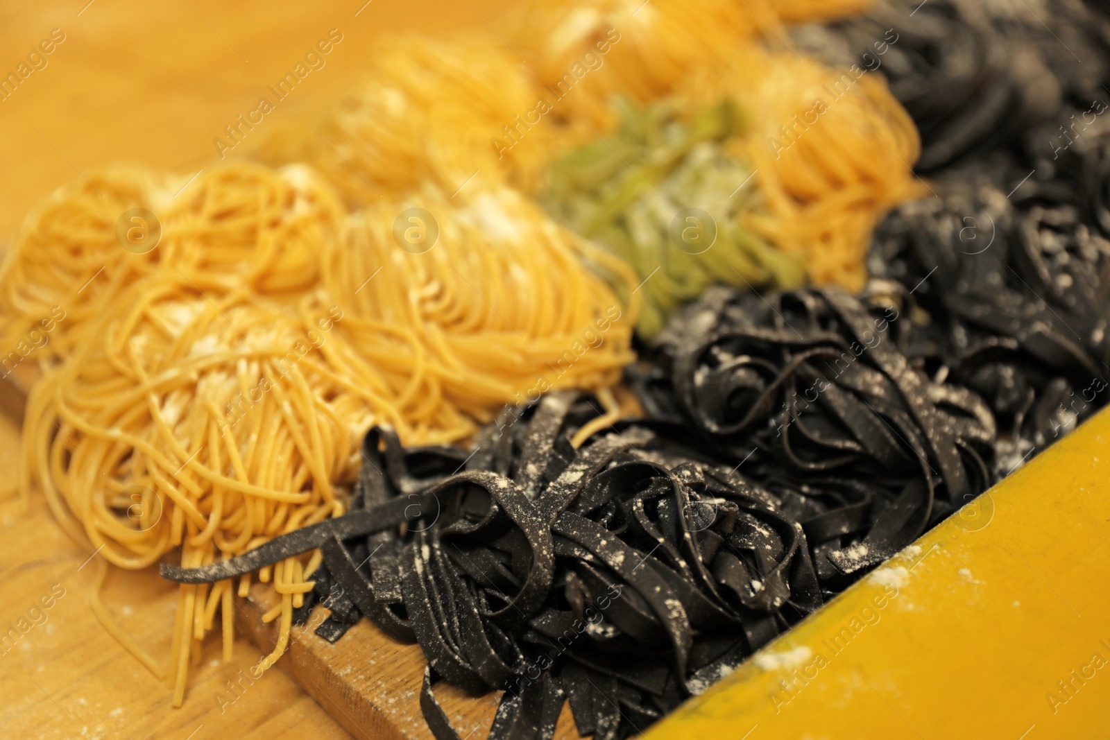 Photo of Natural colorful raw noodles on wooden table, closeup