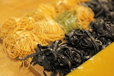 Photo of Natural colorful raw noodles on wooden table, closeup