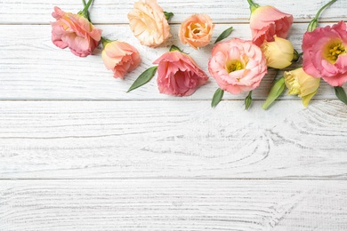 Photo of Flat lay composition with beautiful Eustoma flowers on white wooden table, space for text